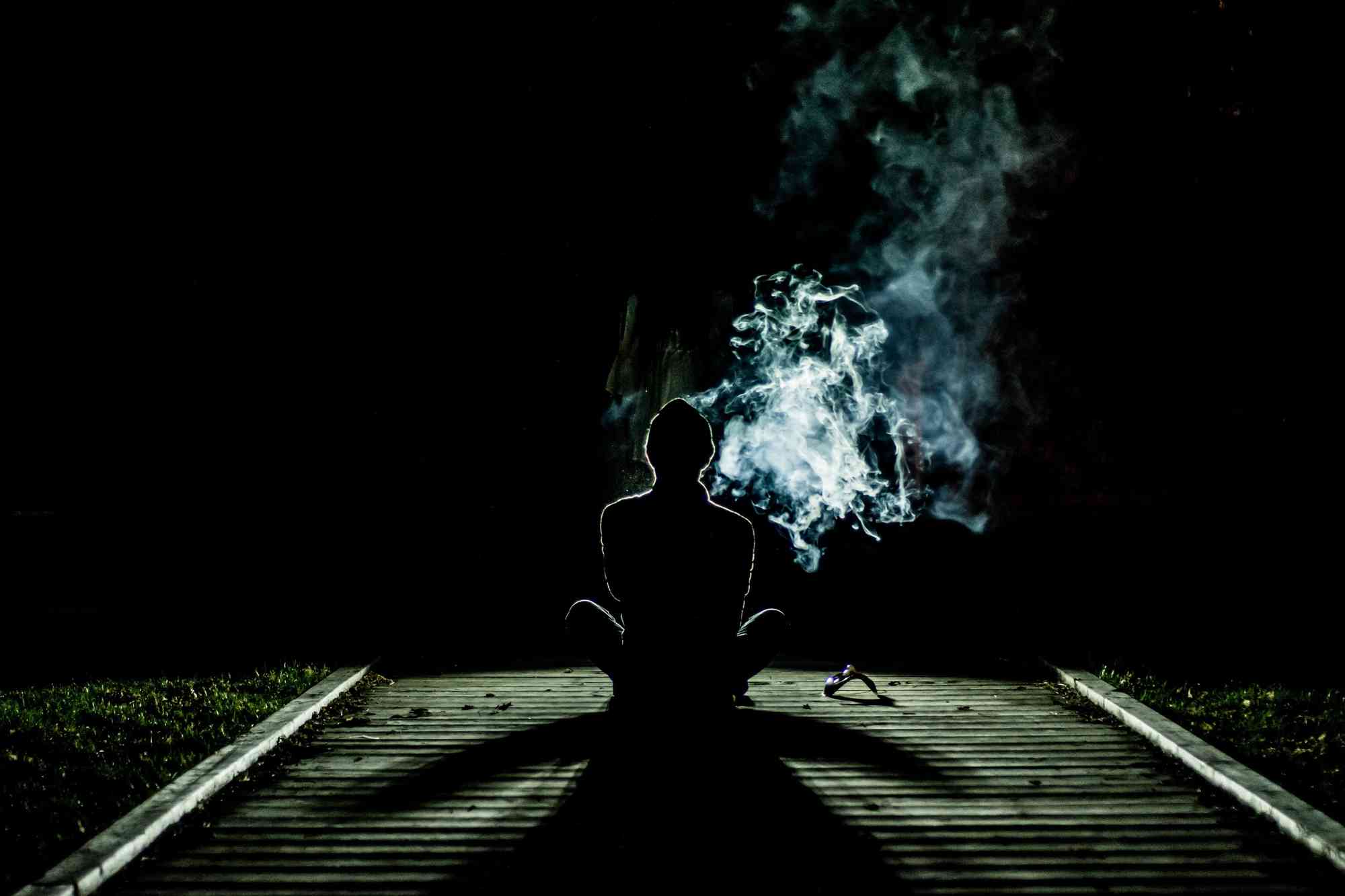 sylwetka osoby palącej w ciemności