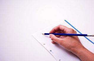 Ręka trzymająca ołówek na tle kartki papieru