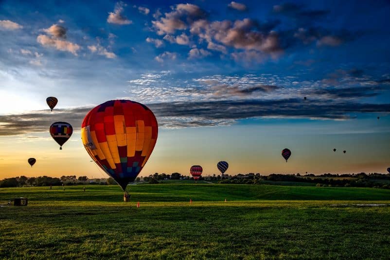 Kolorowe balony wylatujące w powietrze nad polem