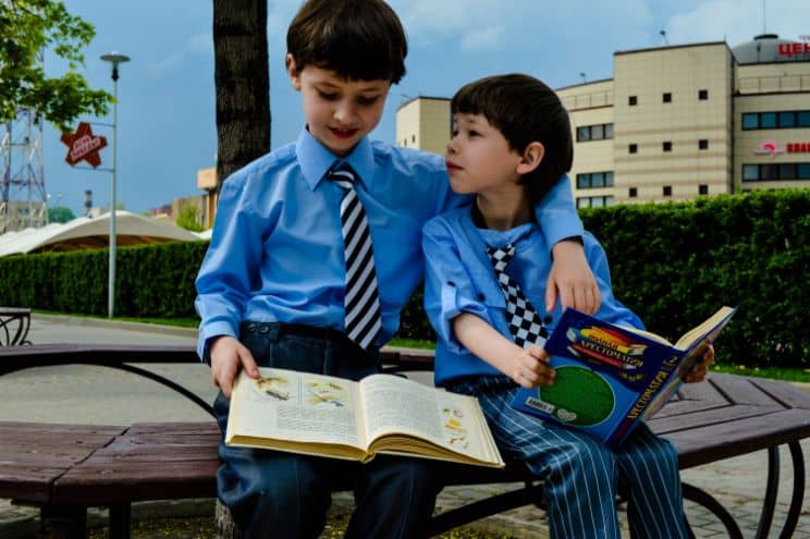 Dwoje dzieci w mundurkach czytające książkę