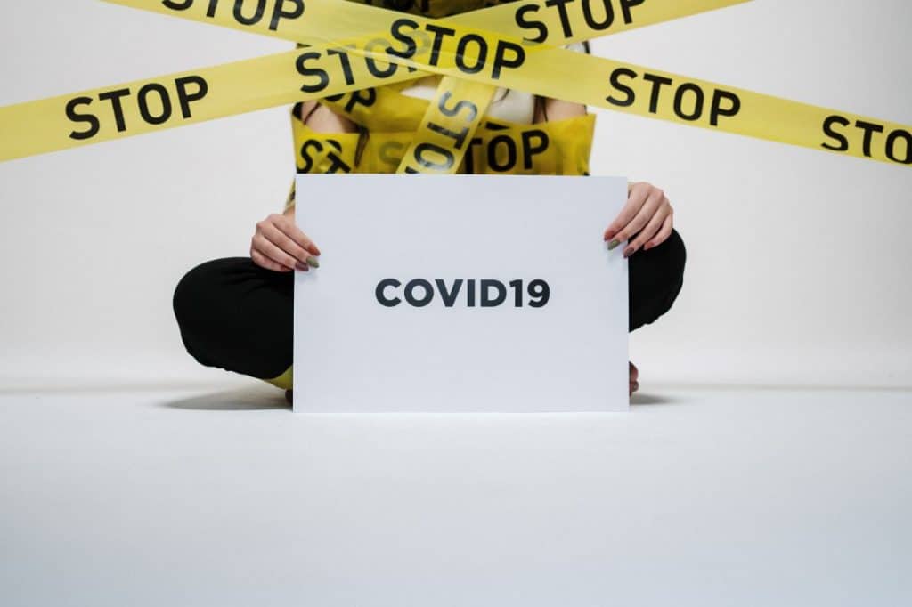 Osoba trzymająca tablicę z napisem COVID-19