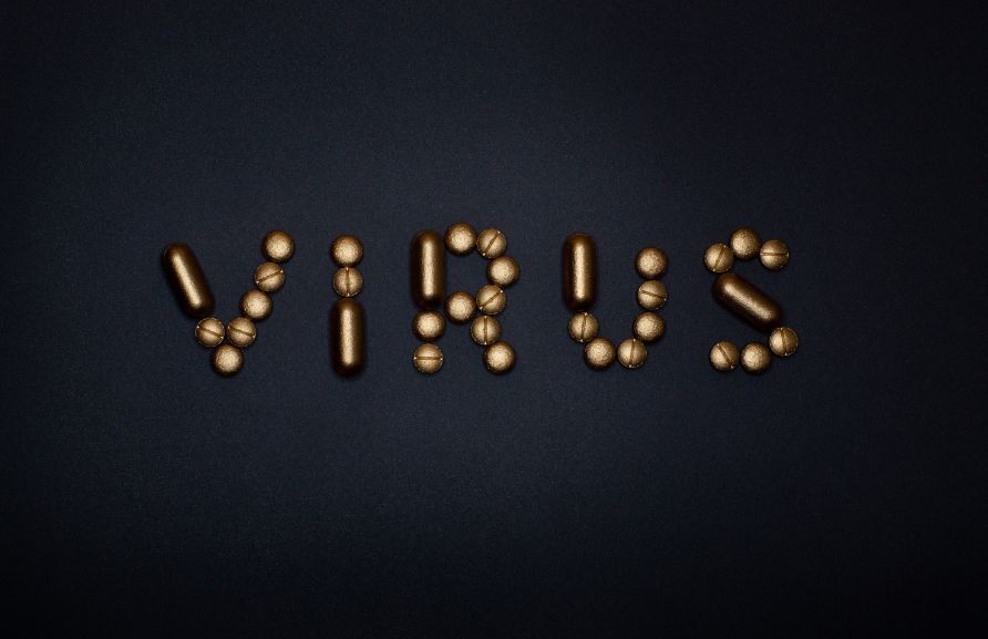 Złote kapsułki ułożone w napis VIRUS