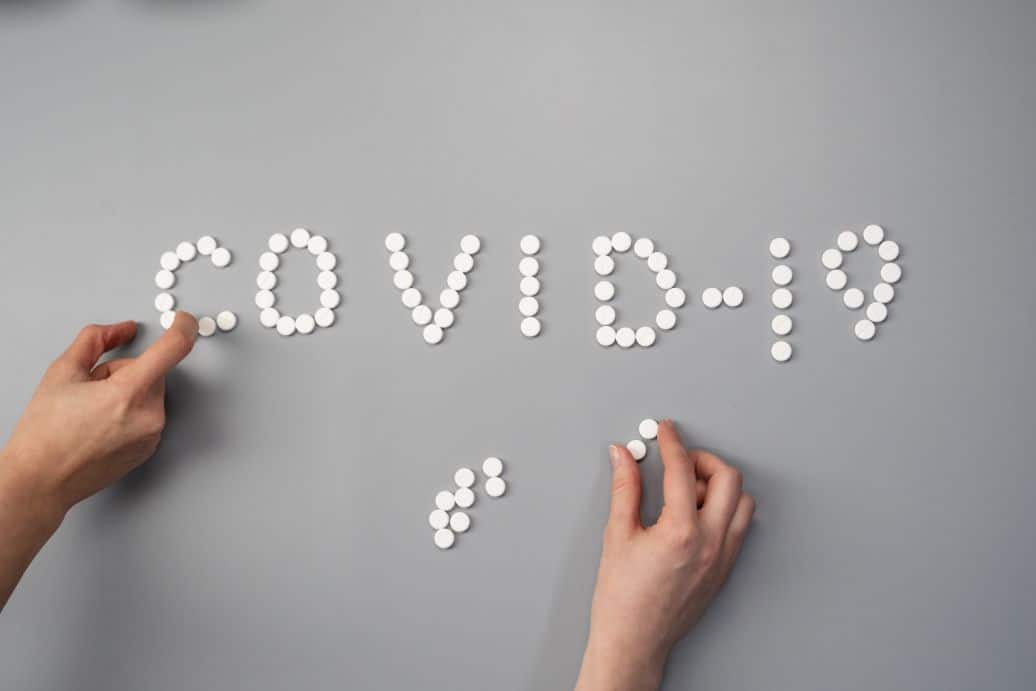 Białe tabletki ułożone w napis COVID-19