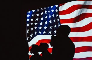 Sylwetki osób na tle flagi amerykańskiej