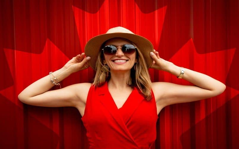 Kobieta w kapeluszu i czerwonej sukience na tle kanadyjskiej flagi