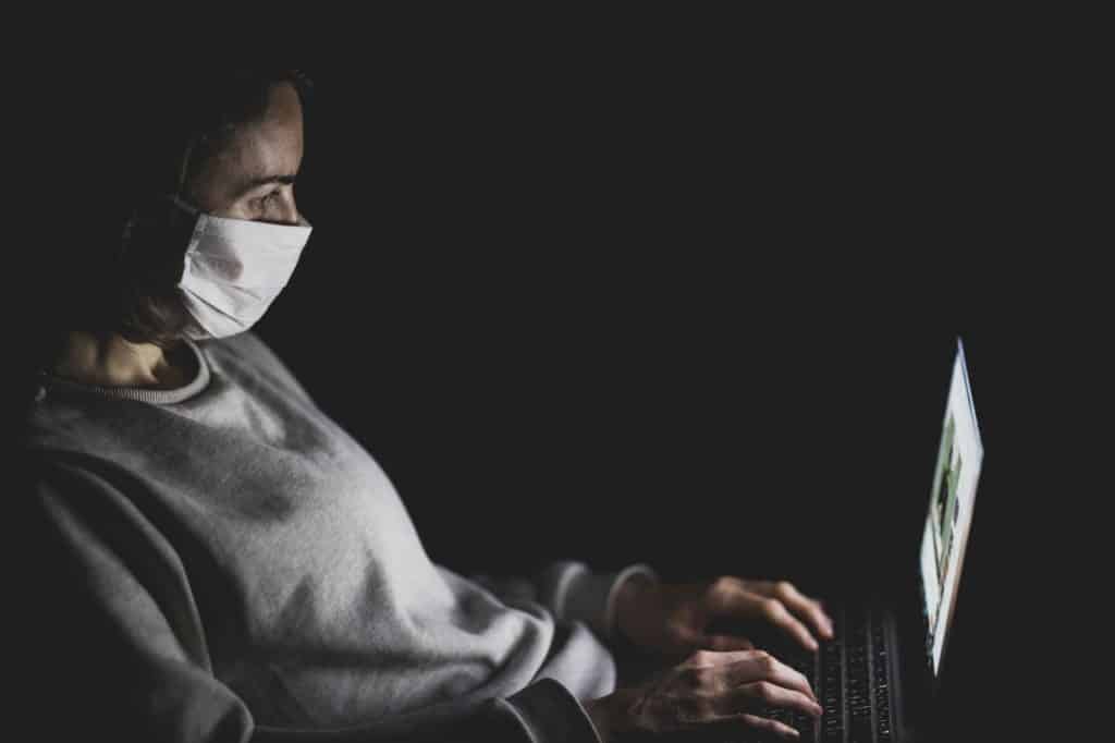 Kobieta w masce medycznej przy laptopie