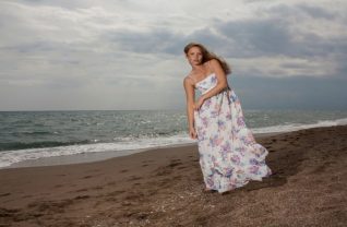 Blondynka w kwiecistej sukience nad brzegiem morza