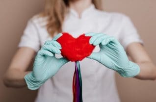 Czerwone serce trzymane w dłoniach kobiety w rękawiczkach
