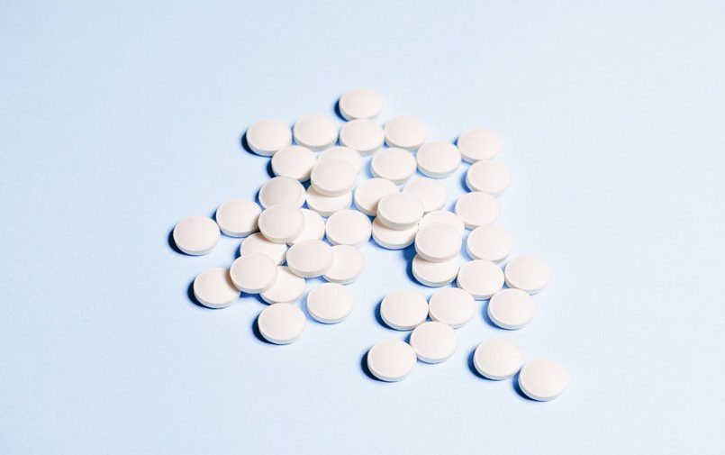 Białe tabletki na niebieskim tle