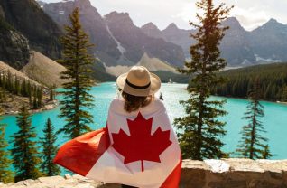 Kobita siedząca w górach owinięta flagą kanadyjską