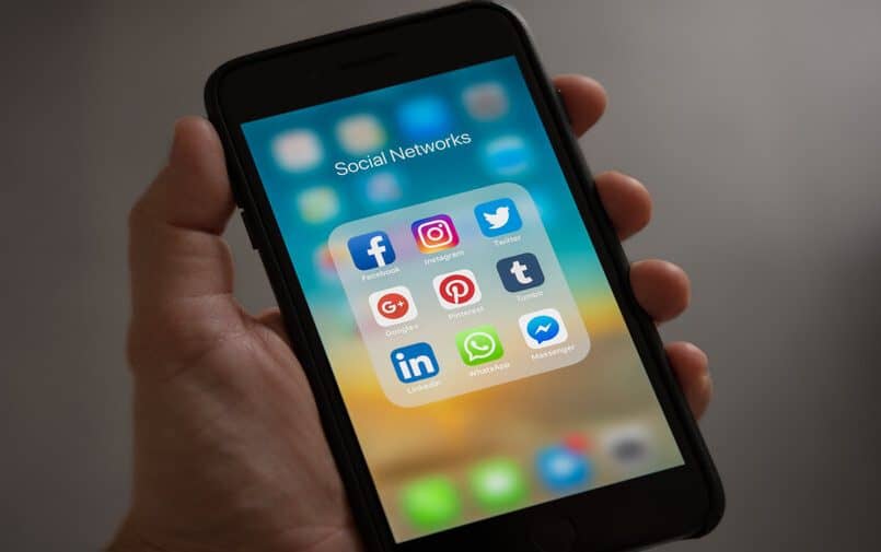 Osoba trzymająca iPhone z ikonkami mediów społecznościowych