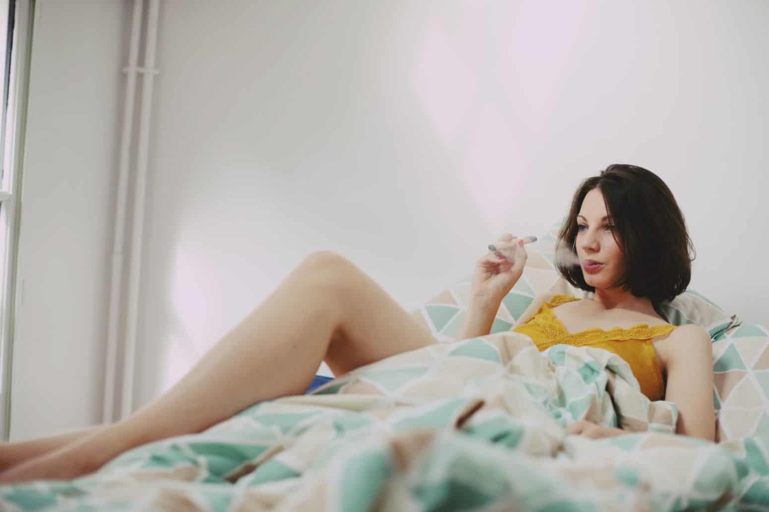 Kobieta w łóżku paląca marihuanę